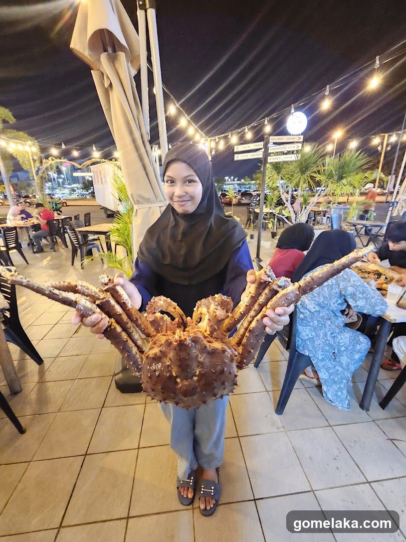 Person holding large crab at outdoor dining area