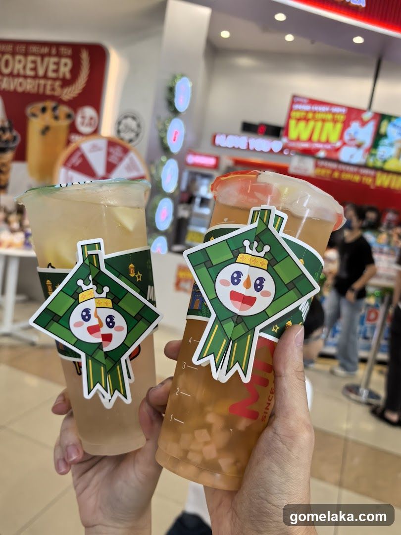 Two beverages with branded stickers held in hands