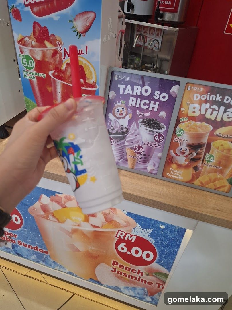 Customer holding a drink in front of promotional displays