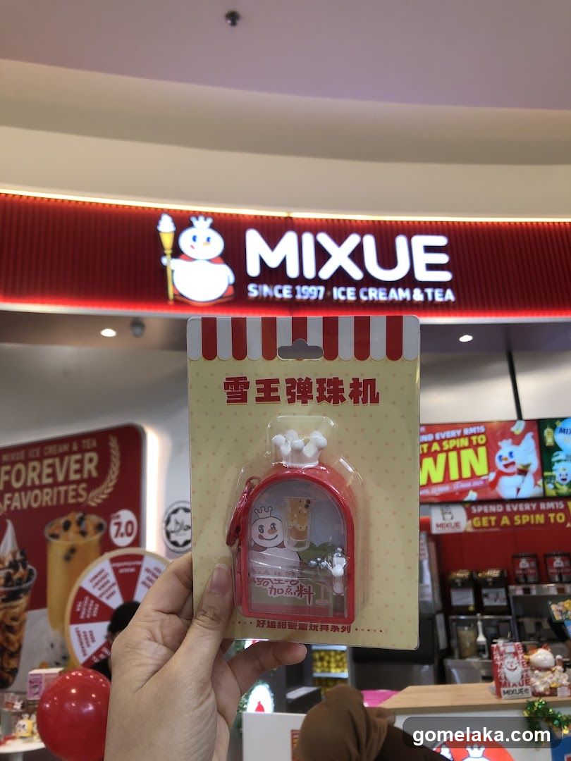 Hand holding branded merchandise in front of MIXUE store