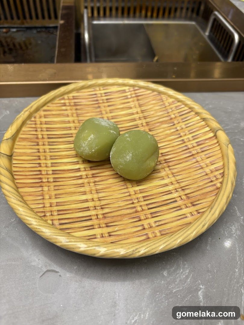 Two green mochi on a woven tray