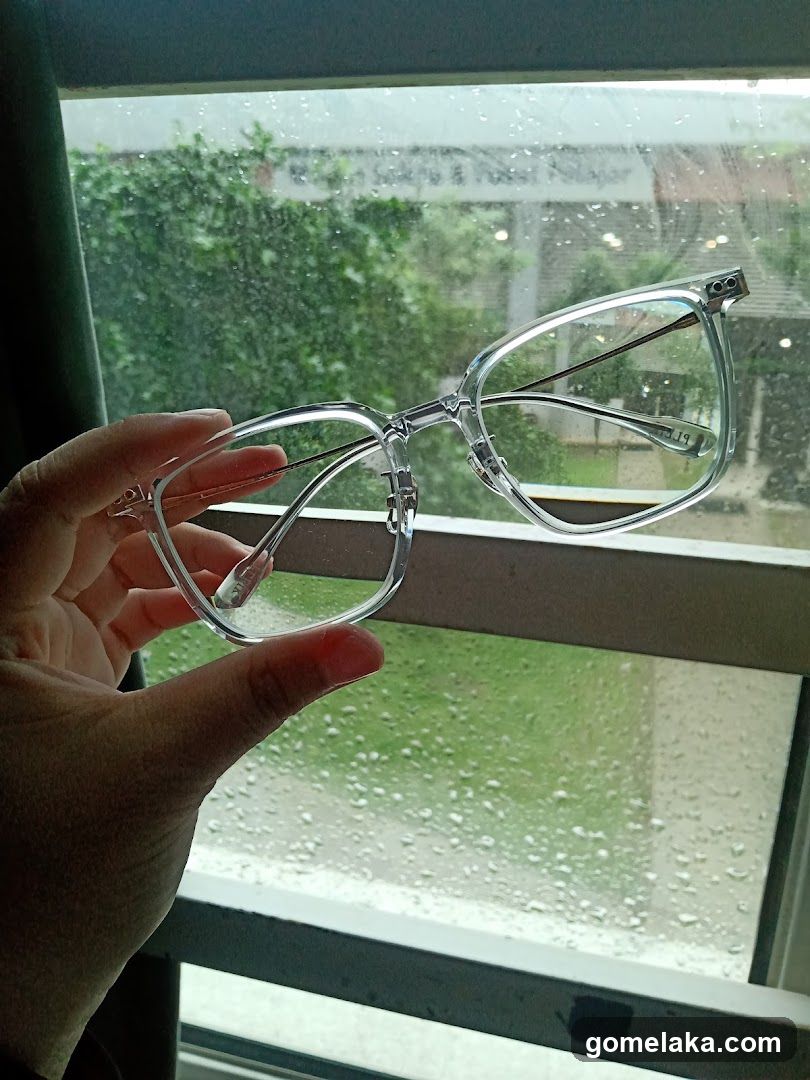 Hand holding glasses in front of rainy window