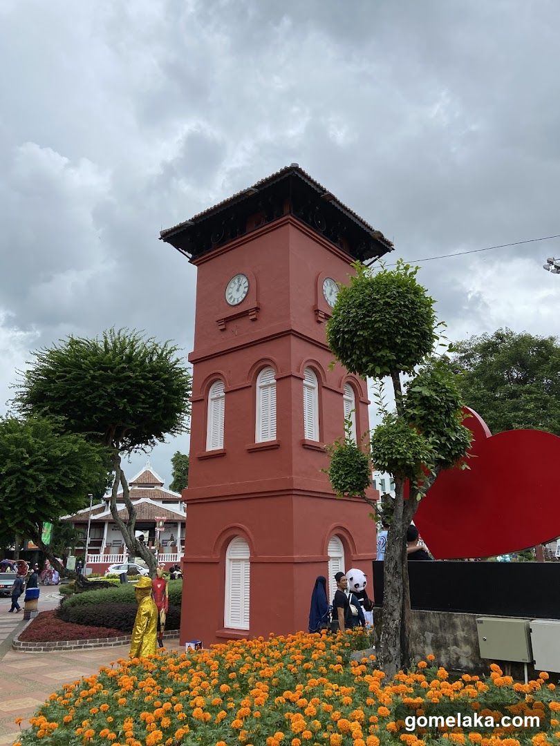 Red Clock Tower with Flower Beds and Trees