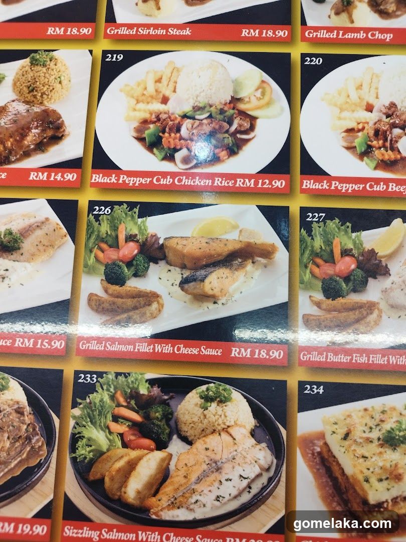Close-up of printed menu with food images and prices in RM. Items include Grilled Sirloin Steak, Black Pepper Cub Chicken Rice, Grilled Salmon Fillet With Cheese Sauce, Sizzling Salmon With Cheese Sauce, etc.