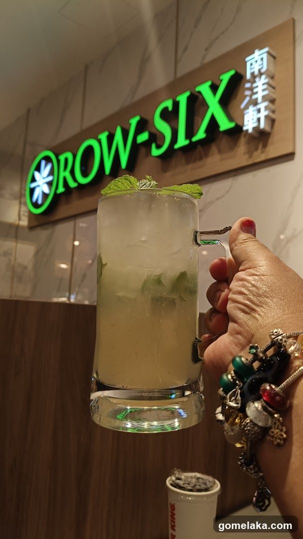 Hand holding drink in front of shop sign