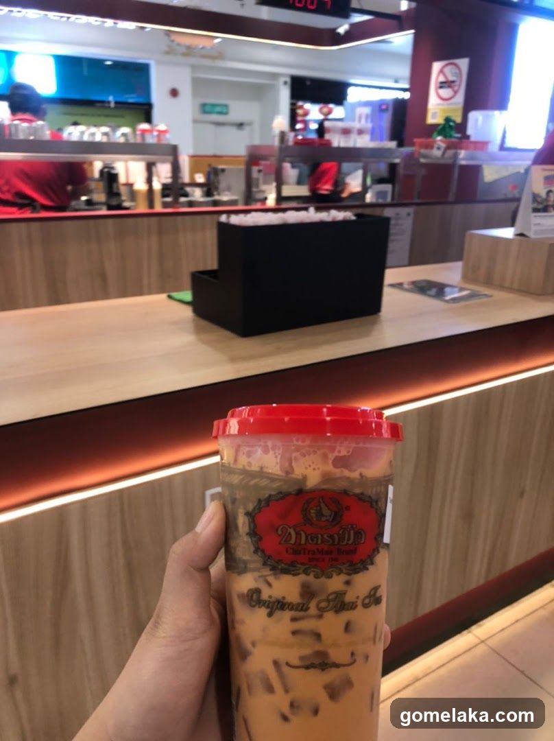 Hand holding Thai tea drink at counter