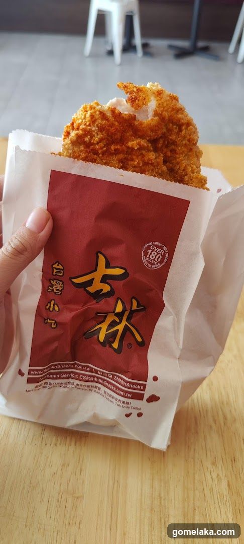 Hand holding fried snack in paper wrapper