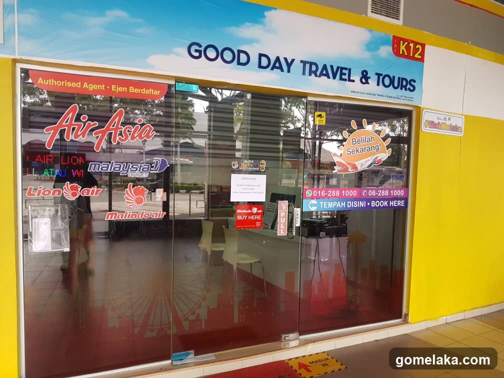 Storefront with glass doors and yellow walls, displaying AirAsia, Lion Air, Malaysia3, MalindoAir logos. Signage includes 'Authorised Agent - Ejen Berdaftar', contact numbers (016-288 1000), and a 'Belilah Sekarang!' sticker. A 'PULL' sign is visible on the door.