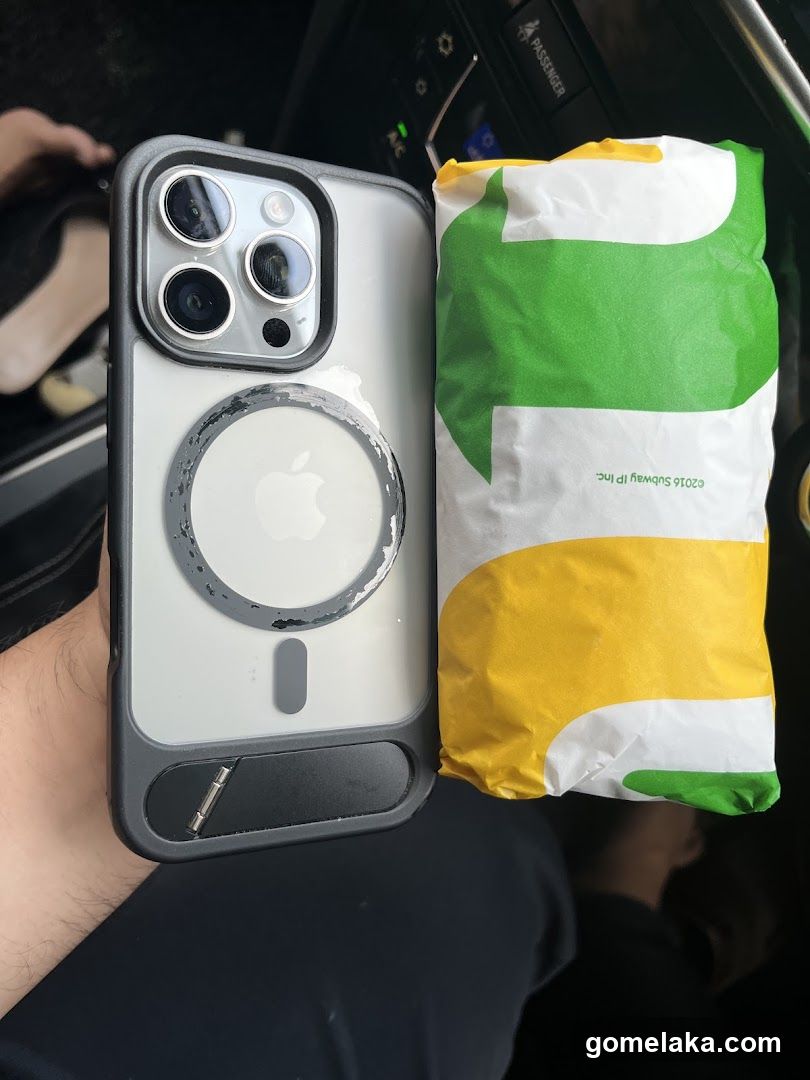 Hand holding phone and food bag inside vehicle