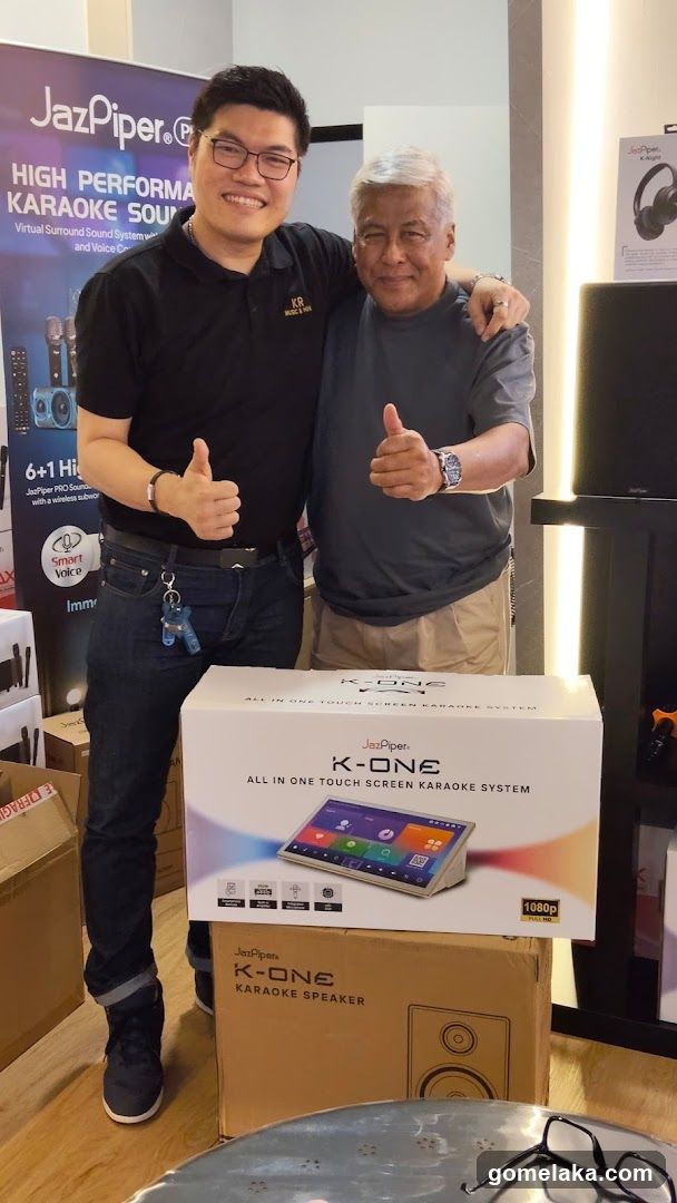 Two men posing with karaoke system box