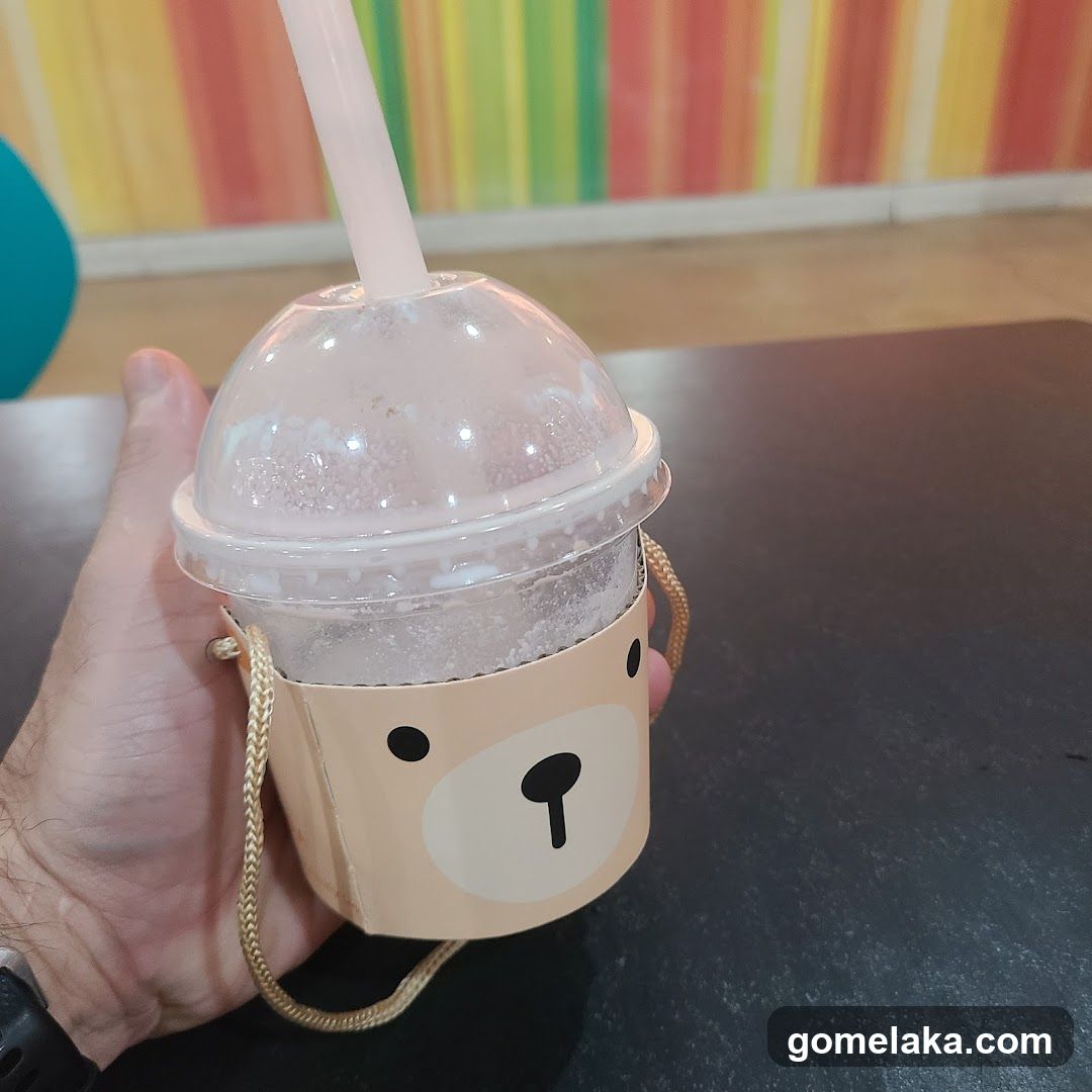 Hand holding a drink with bear-themed cup