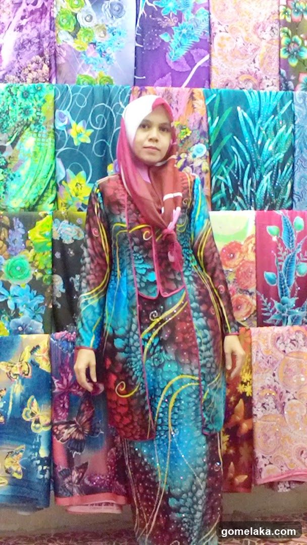 Woman in colorful attire standing before fabric display