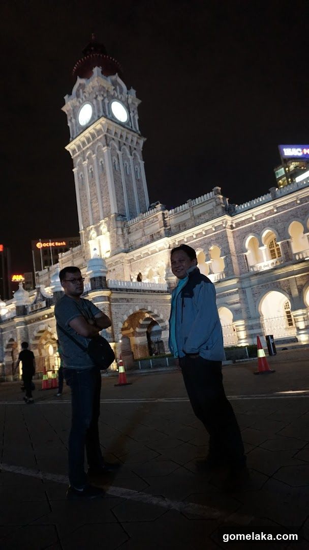 Two individuals posing in front of illuminated historic building at night