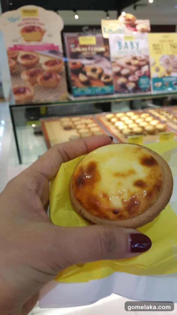 Hand holding egg tart in bakery