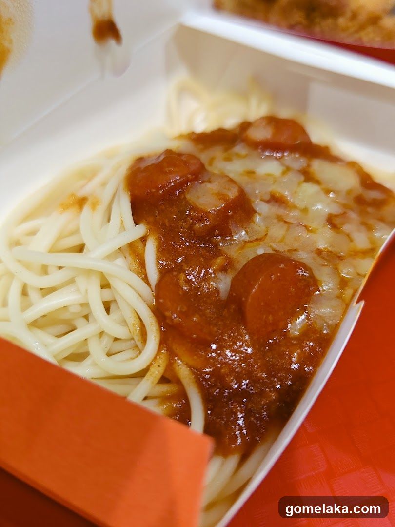 Spaghetti with sauce and sausage in a takeout box