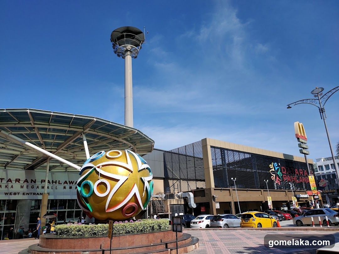 Outdoor shopping area with large sculpture and tower