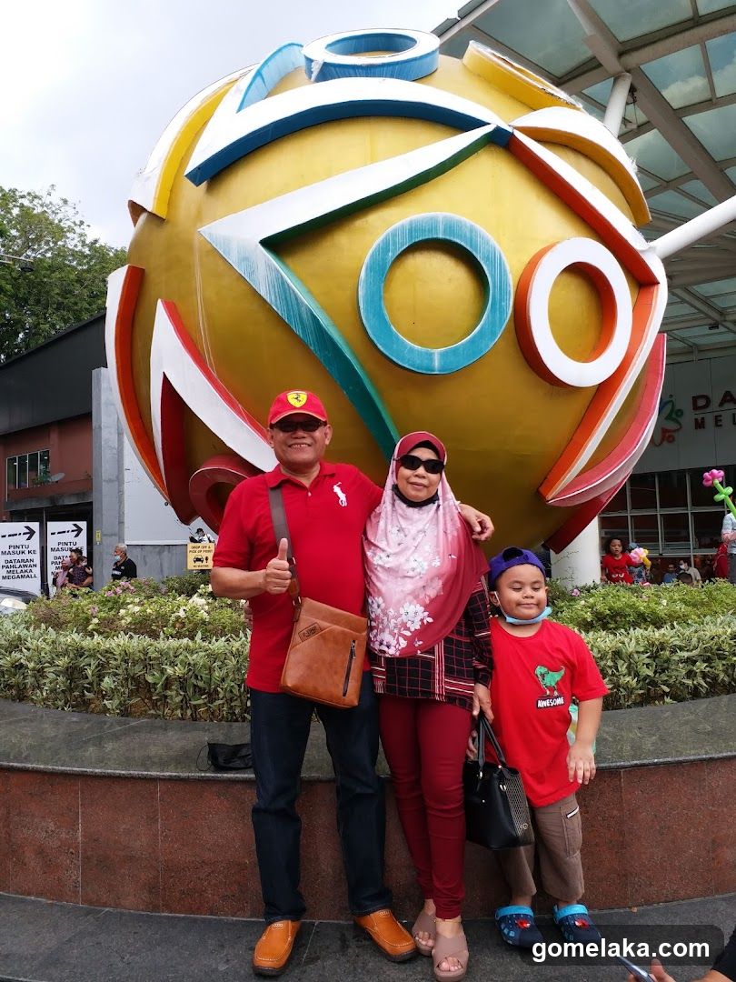 Family posing in front of large zoo sign