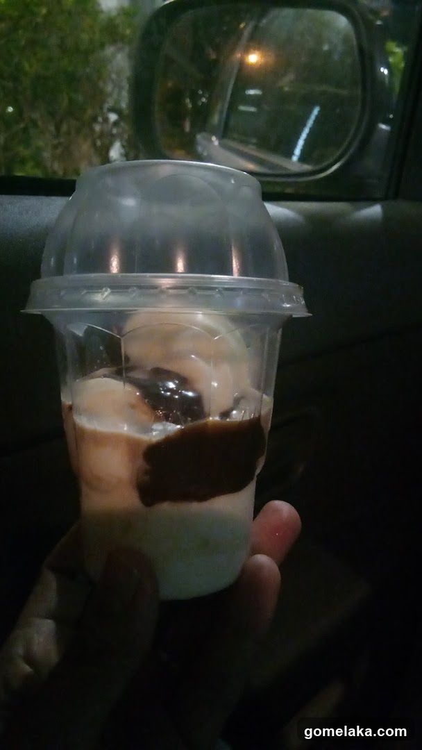 Hand holding dessert cup inside vehicle