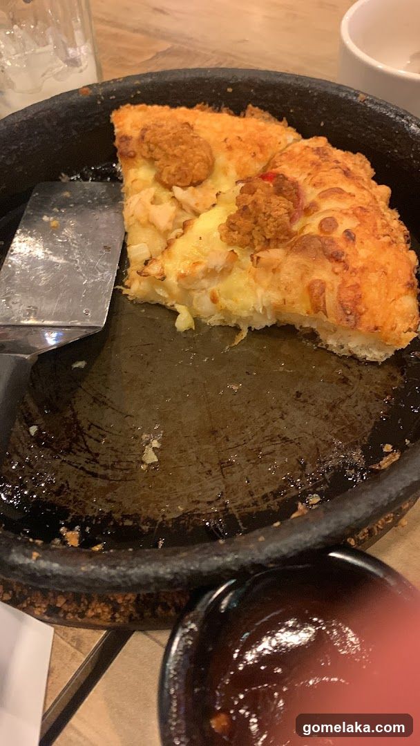 Pizza slice on a pan with utensils and sauce