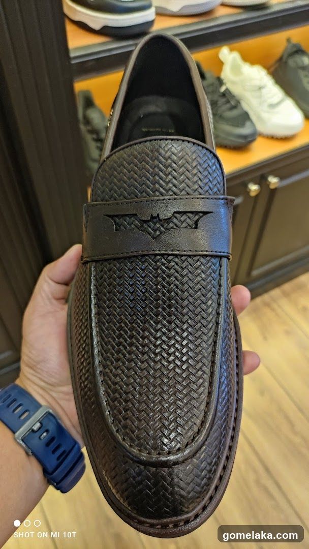 Hand holding Batman-themed loafer